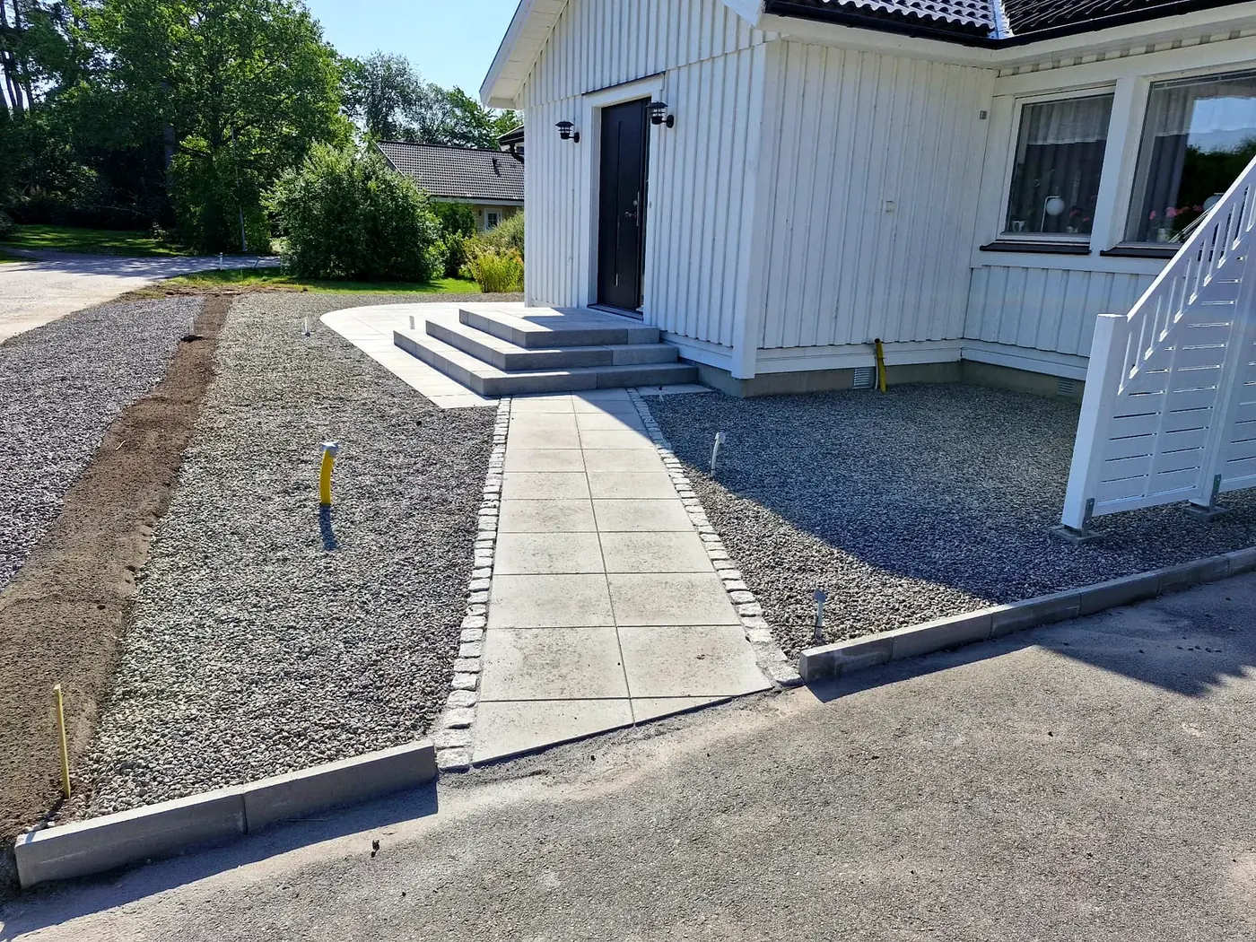 Färdig stenläggning med plattgång och kantsten framför villa i Linköping